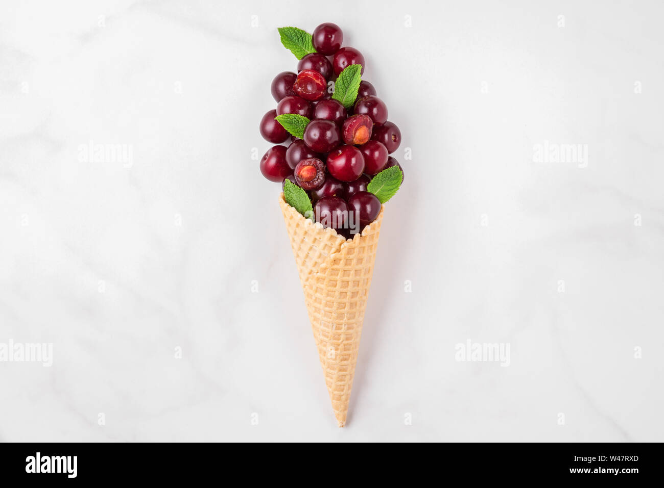 Sommer cherry Beeren mit Minze im Waffle Kegel auf weißem Hintergrund. Sommer essen Konzept. top anzeigen. Flach Stockfoto