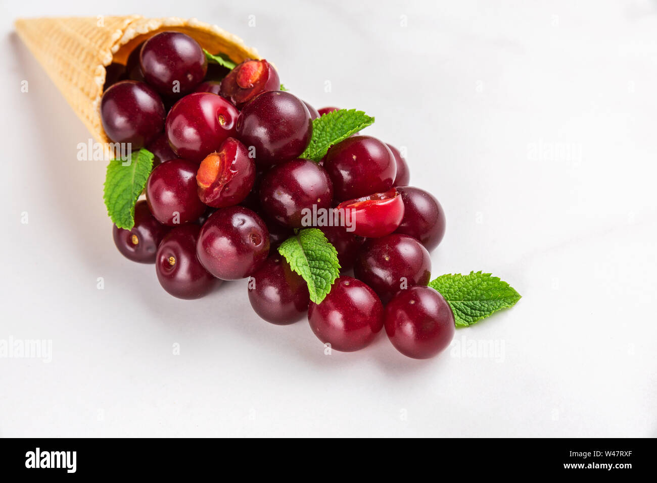 Sommer cherry Beeren mit Minze im Waffle Kegel auf weißem Hintergrund. Sommer essen Konzept. Nach oben Schließen Stockfoto