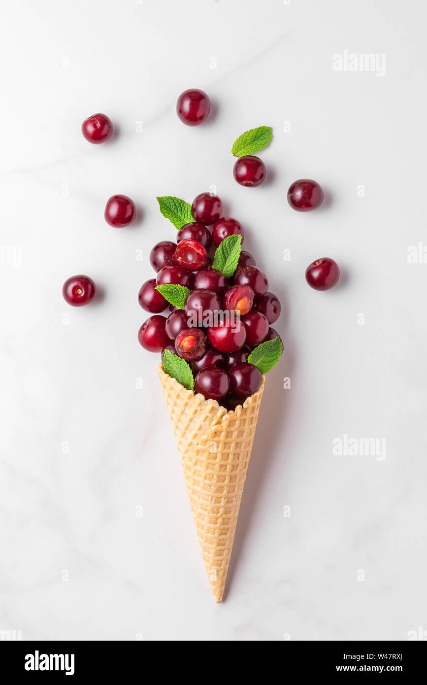 Cherry Beeren mit Minze in Waffel Eiswaffel auf weißem Hintergrund. Sommer essen Konzept. top anzeigen. Flach Stockfoto