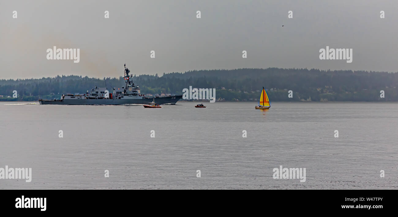 Die USS Ralph Johnson der Arleigh-Burke-Klasse geführte-missile Destroyer und ein kleines Segelboot Stockfoto