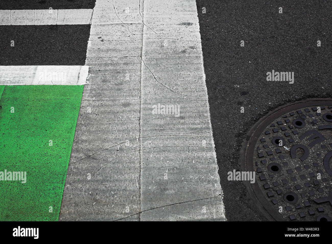 Abstrakte Sicht auf die Straße mit gemalten Linien und Kanaldeckel Stockfoto