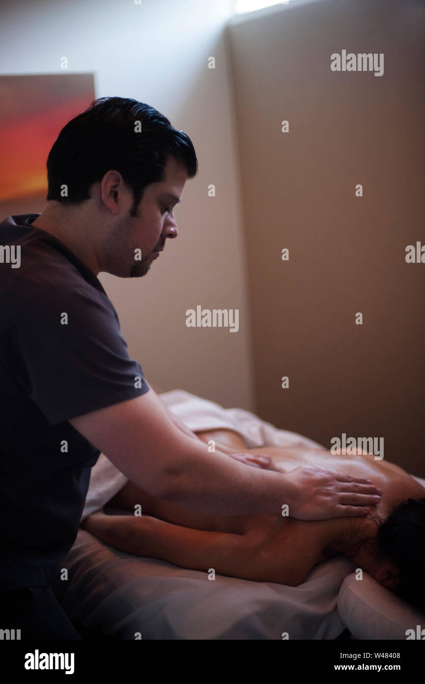 Männliche Therapeuten geben Frau client Massage therapie Karosserie. Der Mann Therapeuten ist Hispanic und seinem Klienten ist kaukasisch. Stockfoto