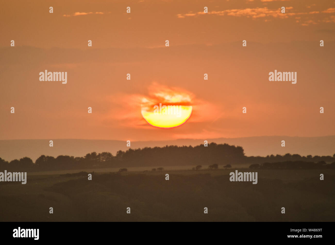 Eastbourne, East Sussex, Großbritannien. Juli 2019..Glorious Sunset Sequence over the misty countryside as Sun dips behind Cloud to reerscheint Minuten später on Horizon. Zwei Sonnenuntergänge an einem Tag. . Stockfoto