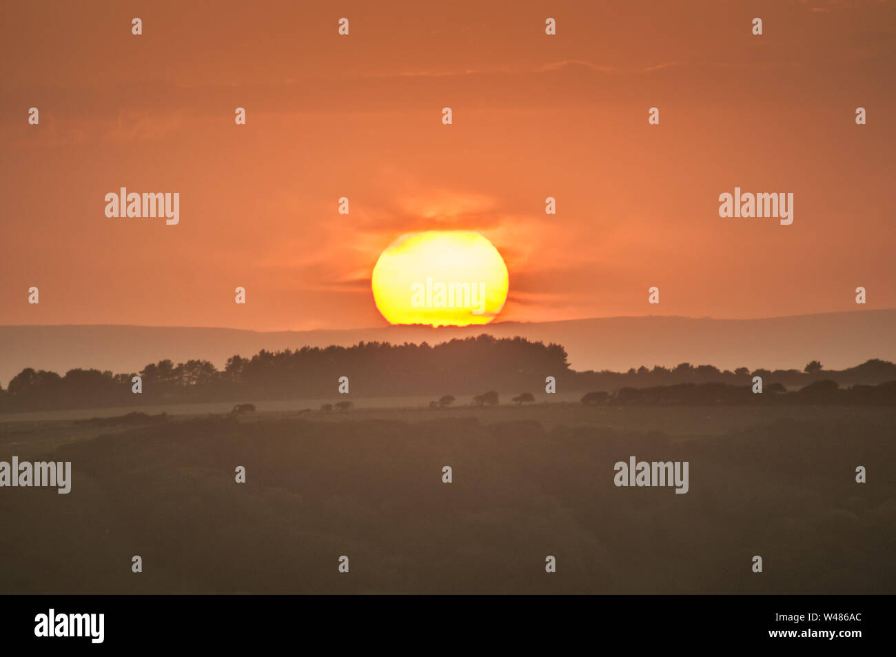 Eastbourne, East Sussex, Großbritannien. Juli 2019..Glorious Sunset Sequence over the misty countryside as Sun dips behind Cloud to reerscheint Minuten später on Horizon. Zwei Sonnenuntergänge an einem Tag. . Stockfoto
