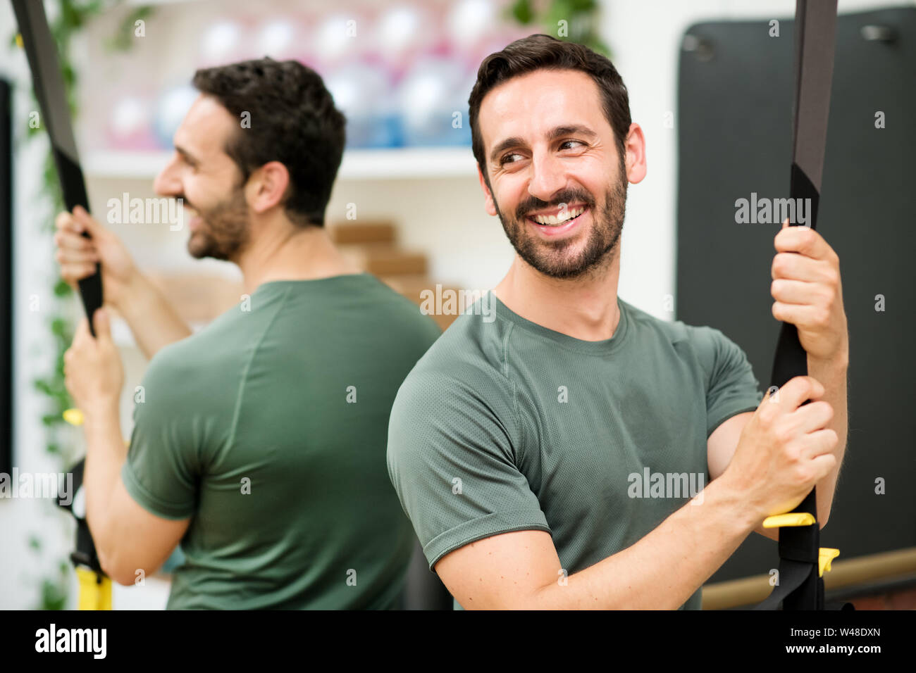 Lächelnd Athlet Mann entspannen vor TRX Training im Fitnessraum Stockfoto
