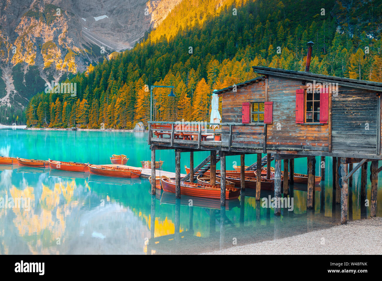 Malerischen alpinen See und schönen Herbst Landschaft mit gelben Lärchen. Beliebte touristische Destination mit Booten aus Holz und niedlichen Holz- Bootshaus, Stockfoto