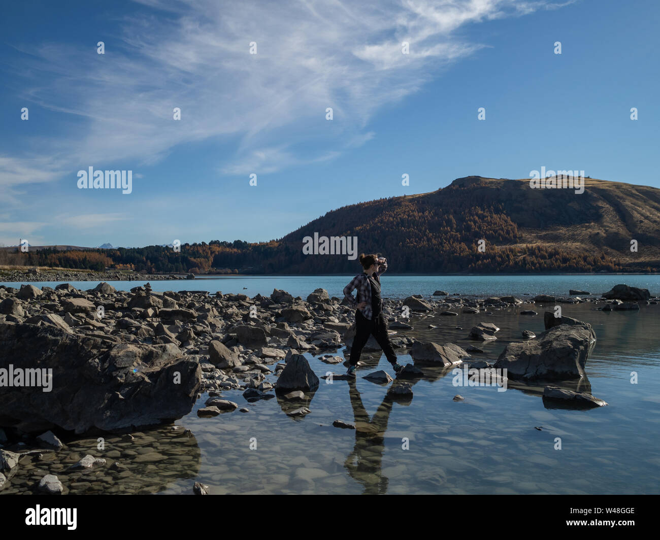 Eine Person am Ufer des Lake Tekapo, Neuseeland, mit türkisblauem Wasser Stockfoto