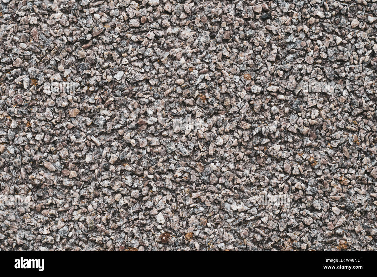 Hintergrund der kleinen braunen und grauen Steinen. Grobe Steinmauer, abstrakte Muster. Oberfläche, rock Textur. Stockfoto
