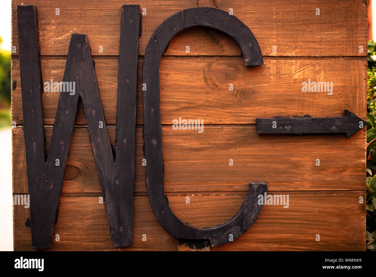 Inschrift WC auf ein Holzbrett. Pfeil von Wc, Schild. Von schwarzen Buchstaben Text. Braunes Holz Textur. Stockfoto