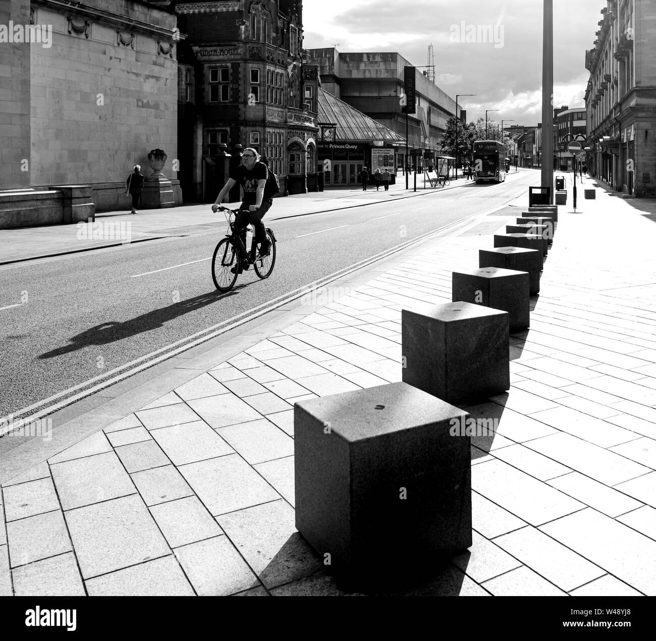 Radfahrer in Hull in Yorkshire, im Zentrum der Stadt zwischen Geschäften und Gebäuden in Schwarz und Weiß und Schatten Stockfoto