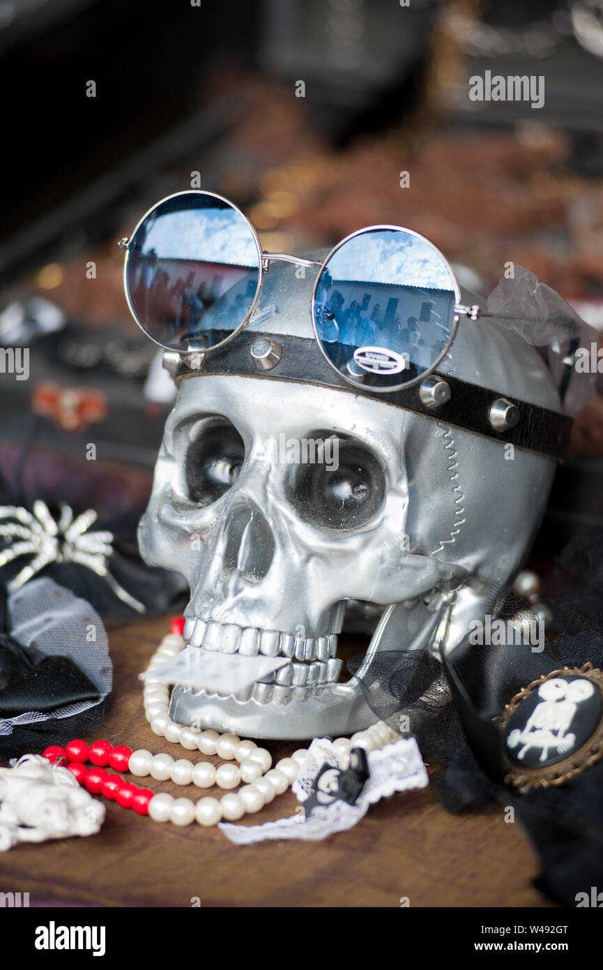 Ein Totenkopf Silber mit Brillen und andere Accessoires auf einem vintage Marktstand. Stockfoto