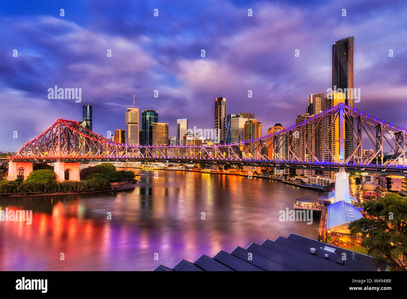 Bright Lights der Story Bridge in Brisbane in Brisbane River vor der hoch aufragenden Türmen, CBD. Vor Sonnenaufgang Bild mit Reflexion der Illuminati Stockfoto