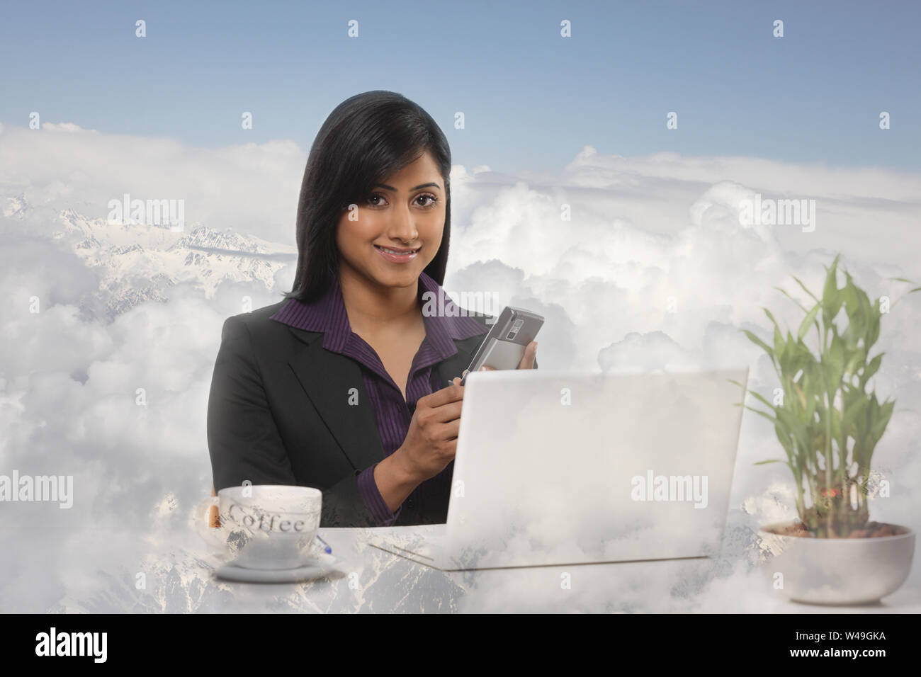 Geschäftsfrau, die ein Mobiltelefon in Wolken verwendet Stockfoto