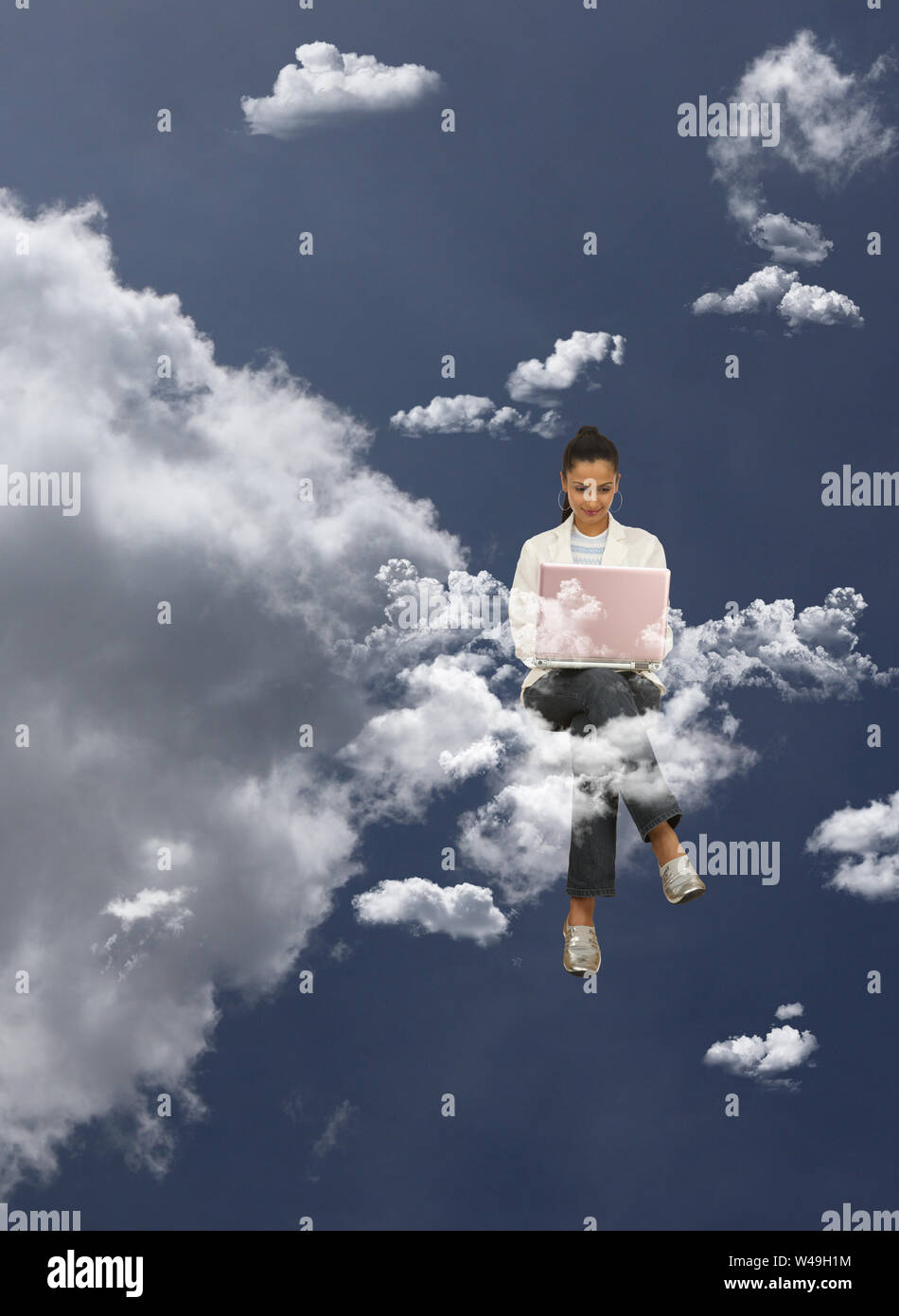 Geschäftsfrau, die auf Wolken sitzt und einen Laptop benutzt Stockfoto