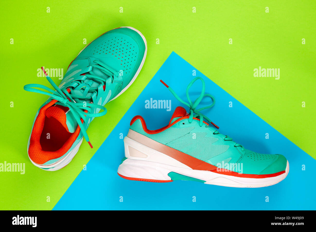 Rot, hellblau, weiß, Paar neue Tennisschuhe im Studio Schuß über grünen, blauen Hintergrund. Direkt von oben. Stockfoto