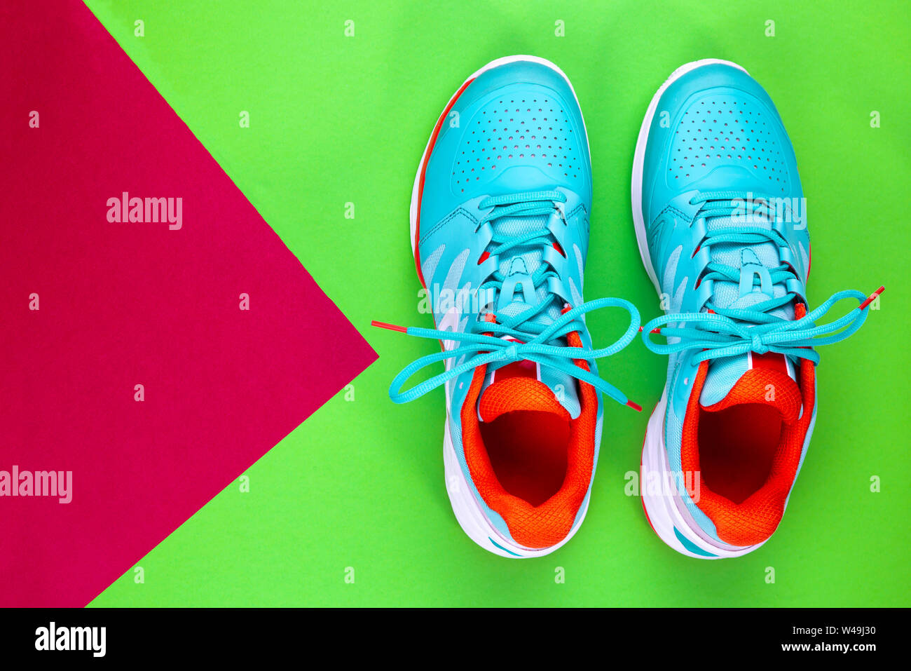 Rot, hellblau, weiß, Paar neue Tennisschuhe im Studio Schuß über grün, lila Hintergrund. Direkt von oben. Stockfoto
