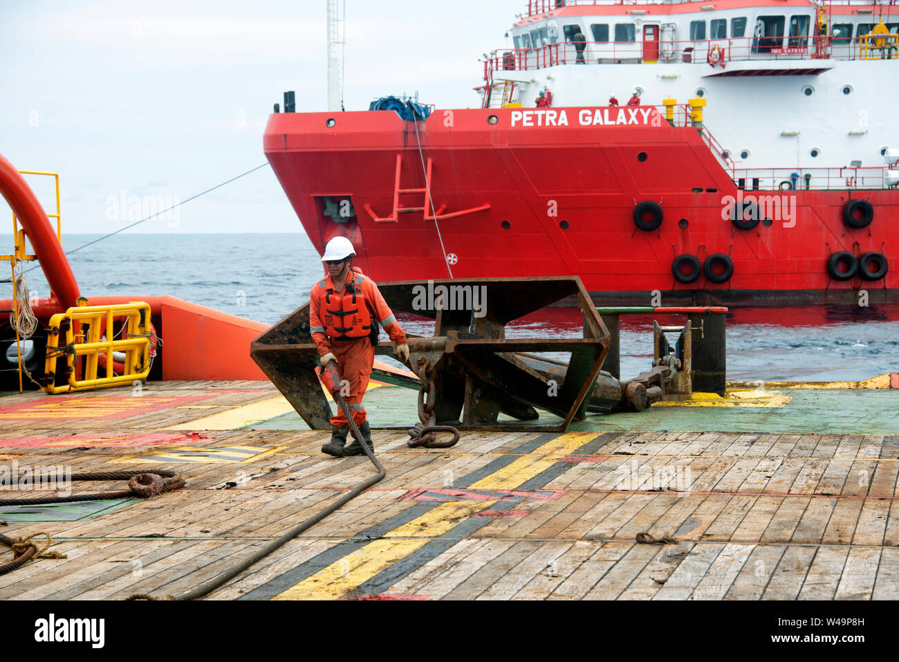 Marine Crew, die Arbeiten für Arbeitsboote vor Anker vor der Küste abwickeln Stockfoto