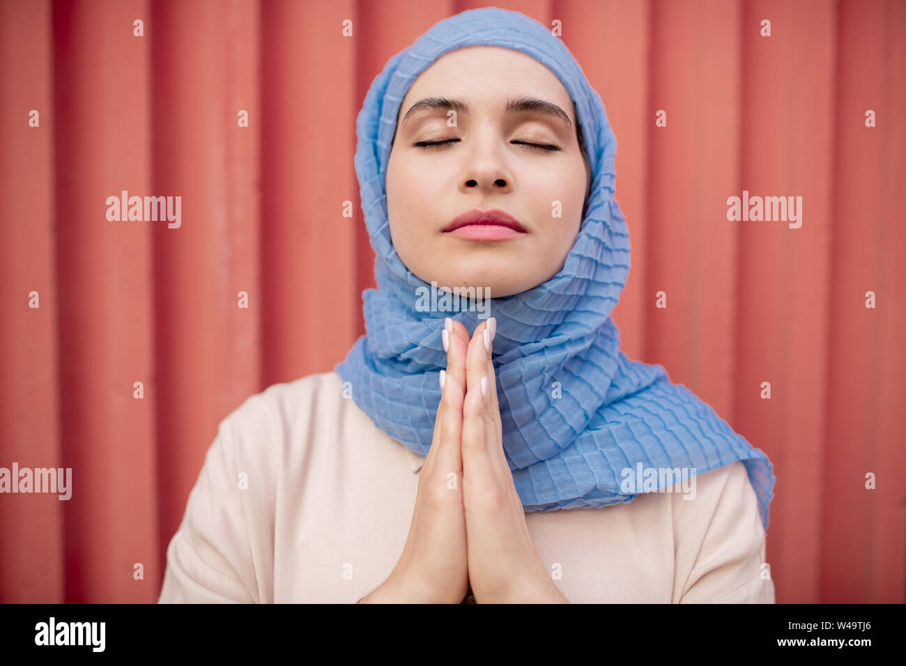 Junge ruhige Frau in der Hijab ihre Hände halten zusammen unter dem Kinn legen Stockfoto