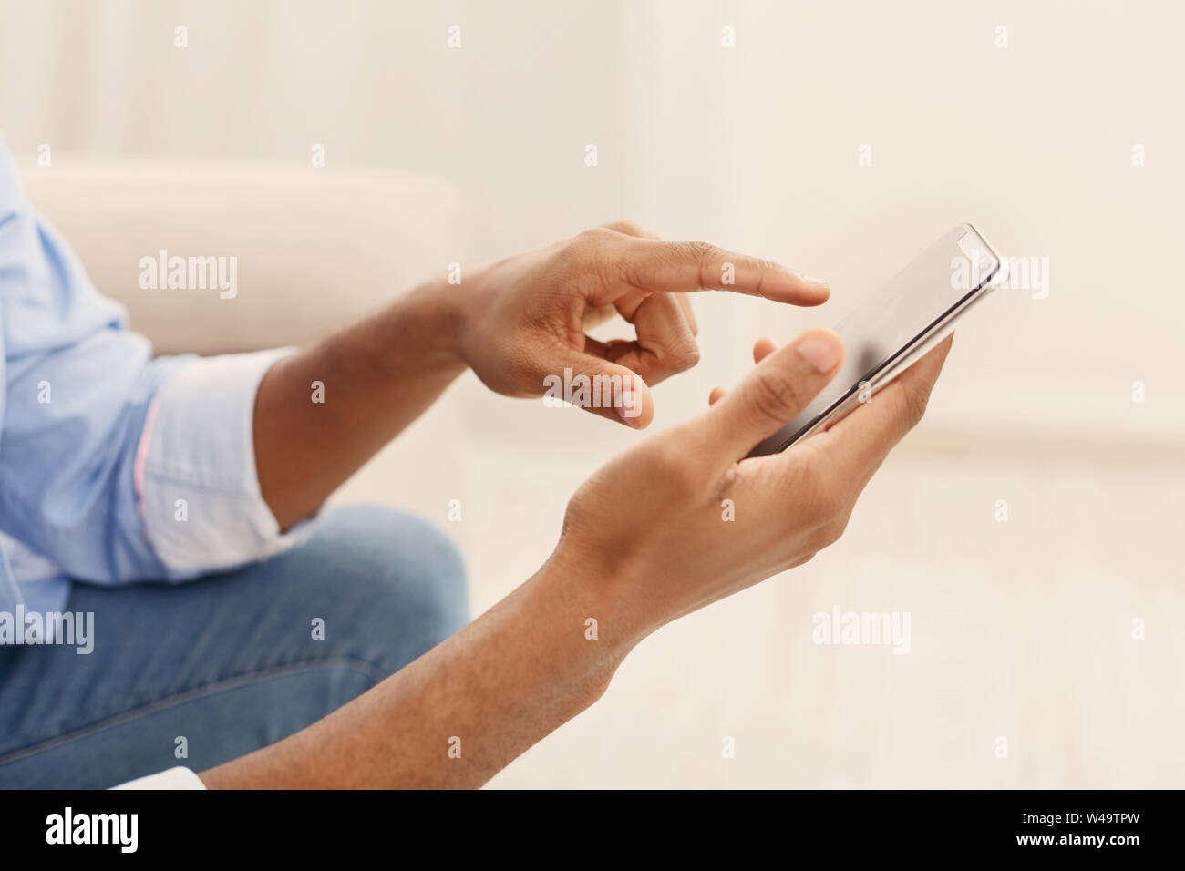 Junger Mann mit modernen Smartphone zu Hause Stockfoto