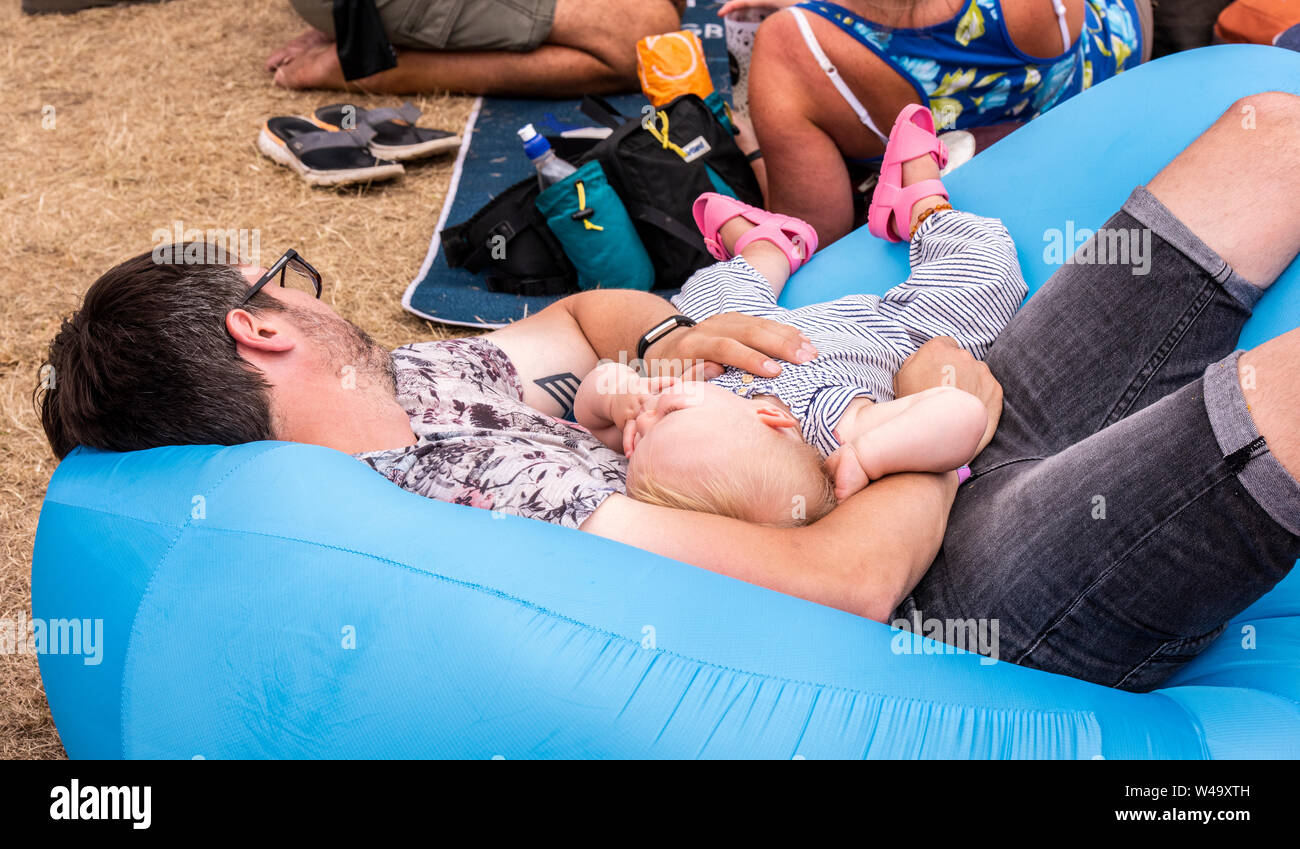 Müde Vater und Baby schlafend auf aufblasbaren bei Latitude Festival, henham Park, Suffolk, Großbritannien, 21. Juli 2019 Stockfoto