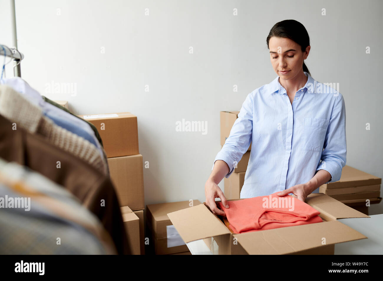 Junge casual Mitarbeiter setzen gefaltet Casualwear in Box in der Verpackung Stockfoto