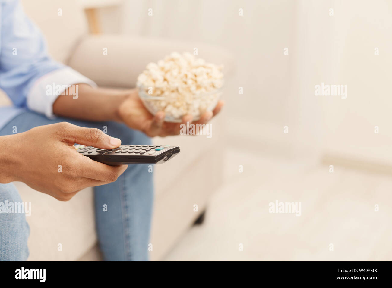 Mann hält TV-Fernbedienung und Popcorn in der Hand Stockfoto