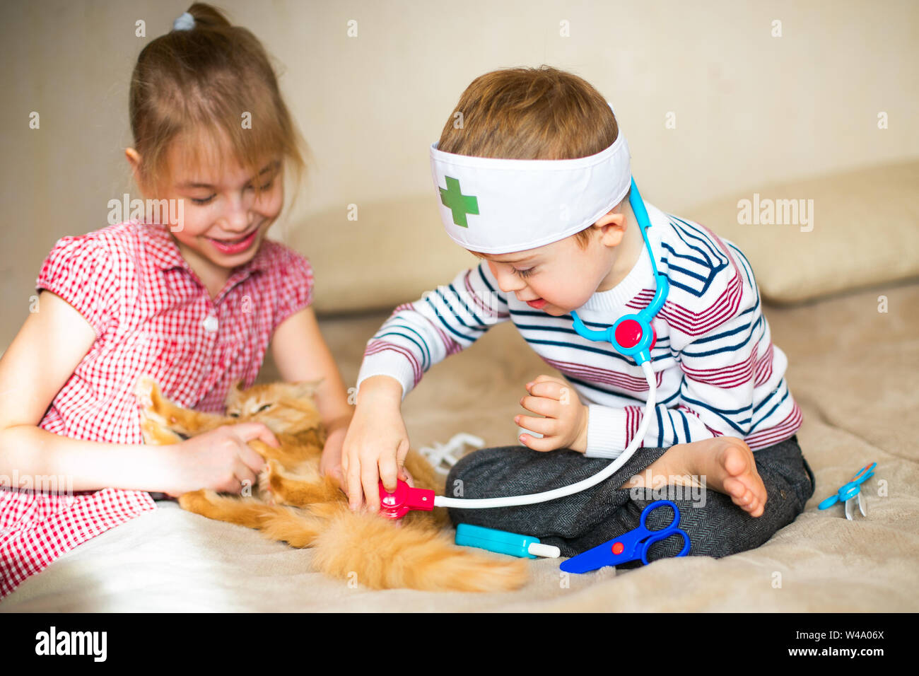 Kleinen Jungen in die Gläser mit Syndrom Dawn und blonde Mädchen spielen mit Spielzeug und Ginger cat. Stockfoto