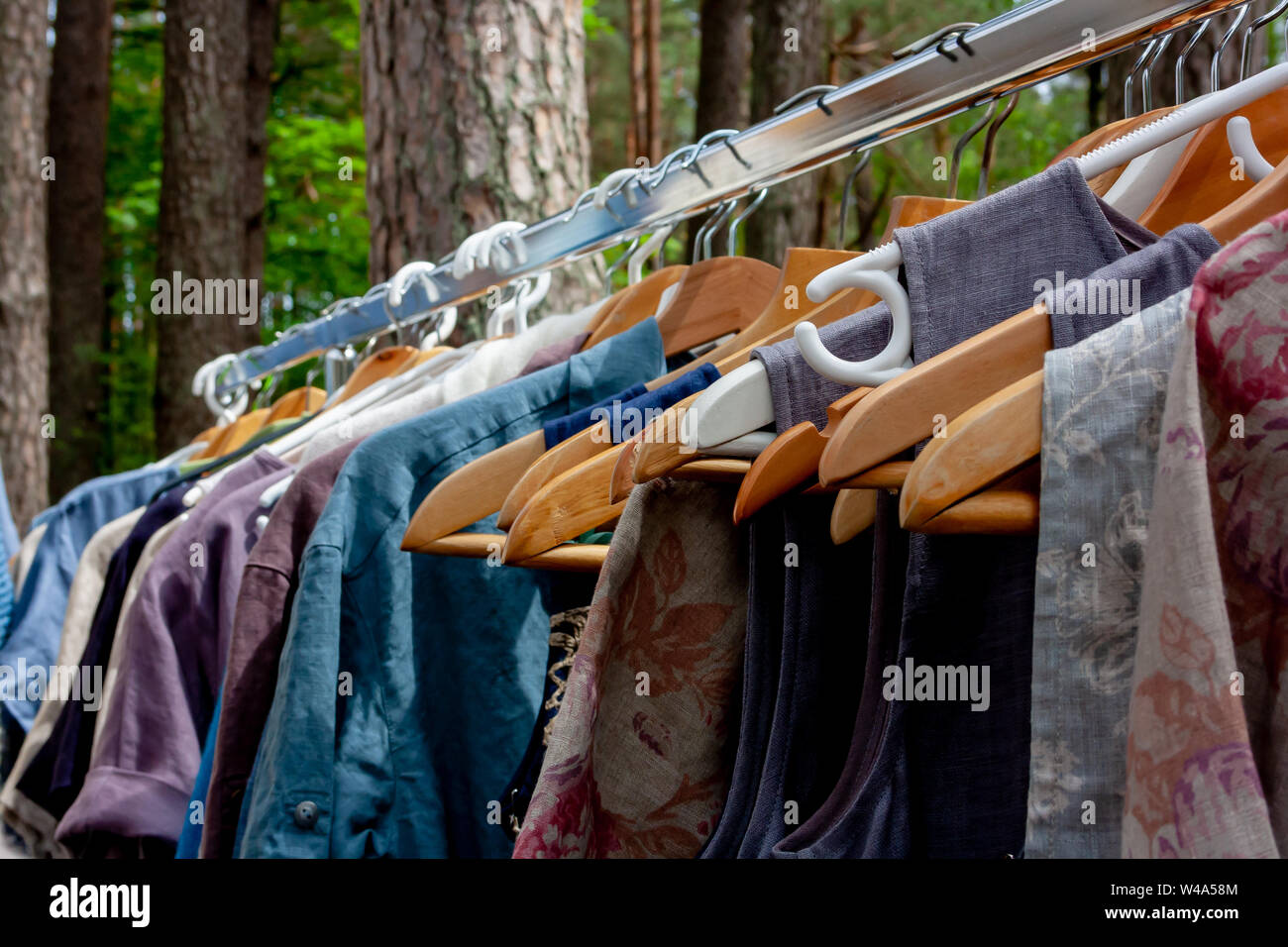 Schöne bunte Kleider auf Kleiderbügeln an einem schönen Sommertag im Park Stockfoto