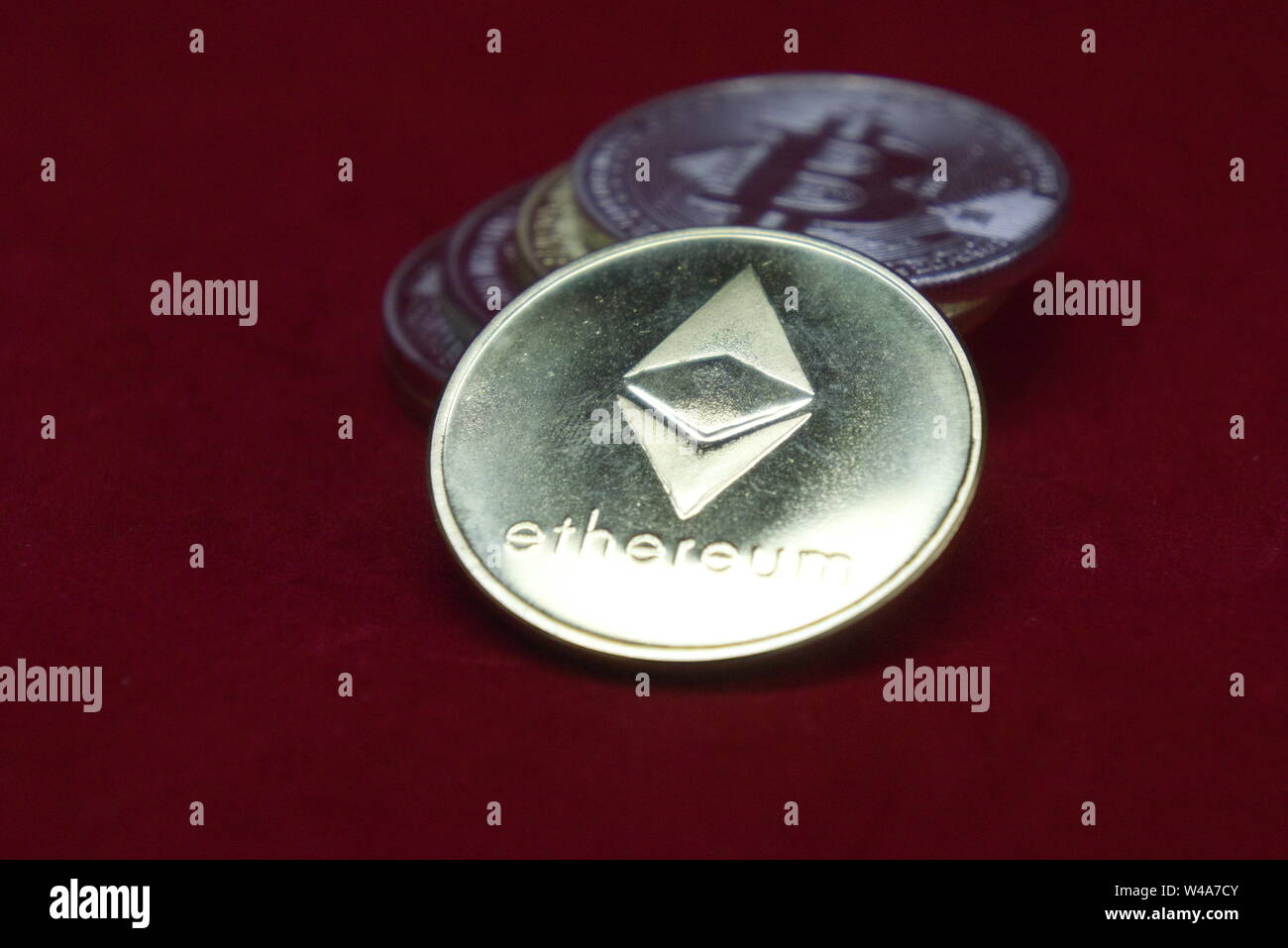 Ein Stapel von Gold und Silber Münzen mit cryptocurrency Astraleums vorne auf einem roten Samt Hintergrund Stockfoto