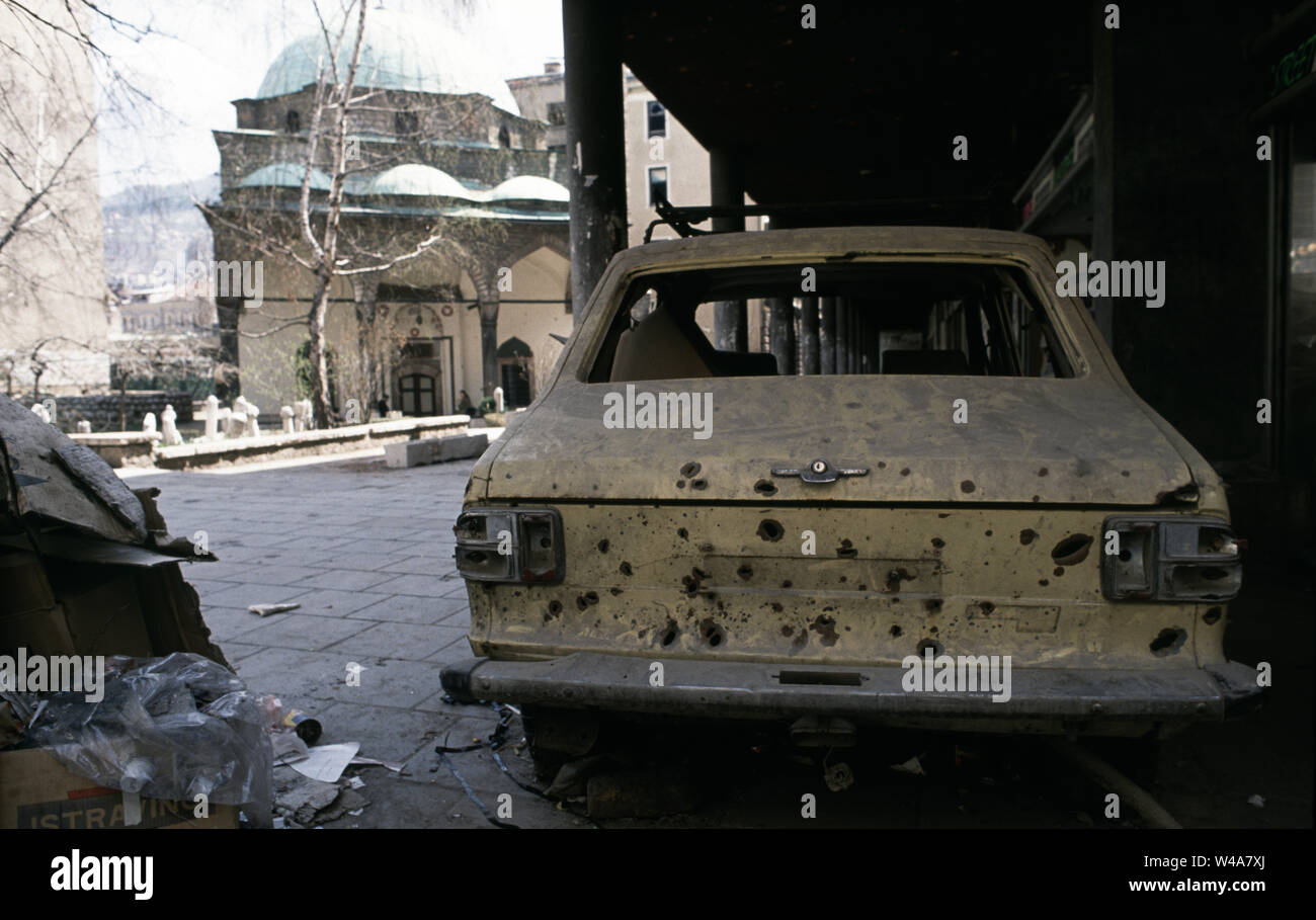 April 1993 21 während der Belagerung von Sarajevo: ein Auto gespickt mit Mörtel bombe Schrapnell" geparkt in der Arcade auf Vase Miskina (heute Ferhadija Straße). Im Hintergrund ist die Ferhadija Moschee. Stockfoto