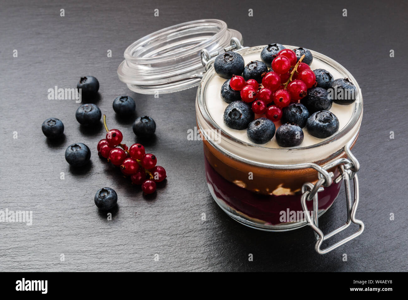 Geschichteten Kuchen Dessert im Glas, Schokolade und Obst Creme, mit Beeren dekoriert. Stockfoto