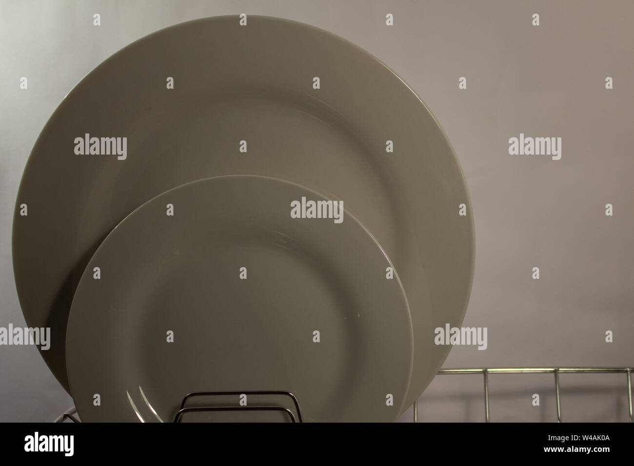 Ein weißer Teller und Seitenplatte am Draht Abtropffläche gegen einen einfachen Hintergrund mit Platz für Kopie Stockfoto