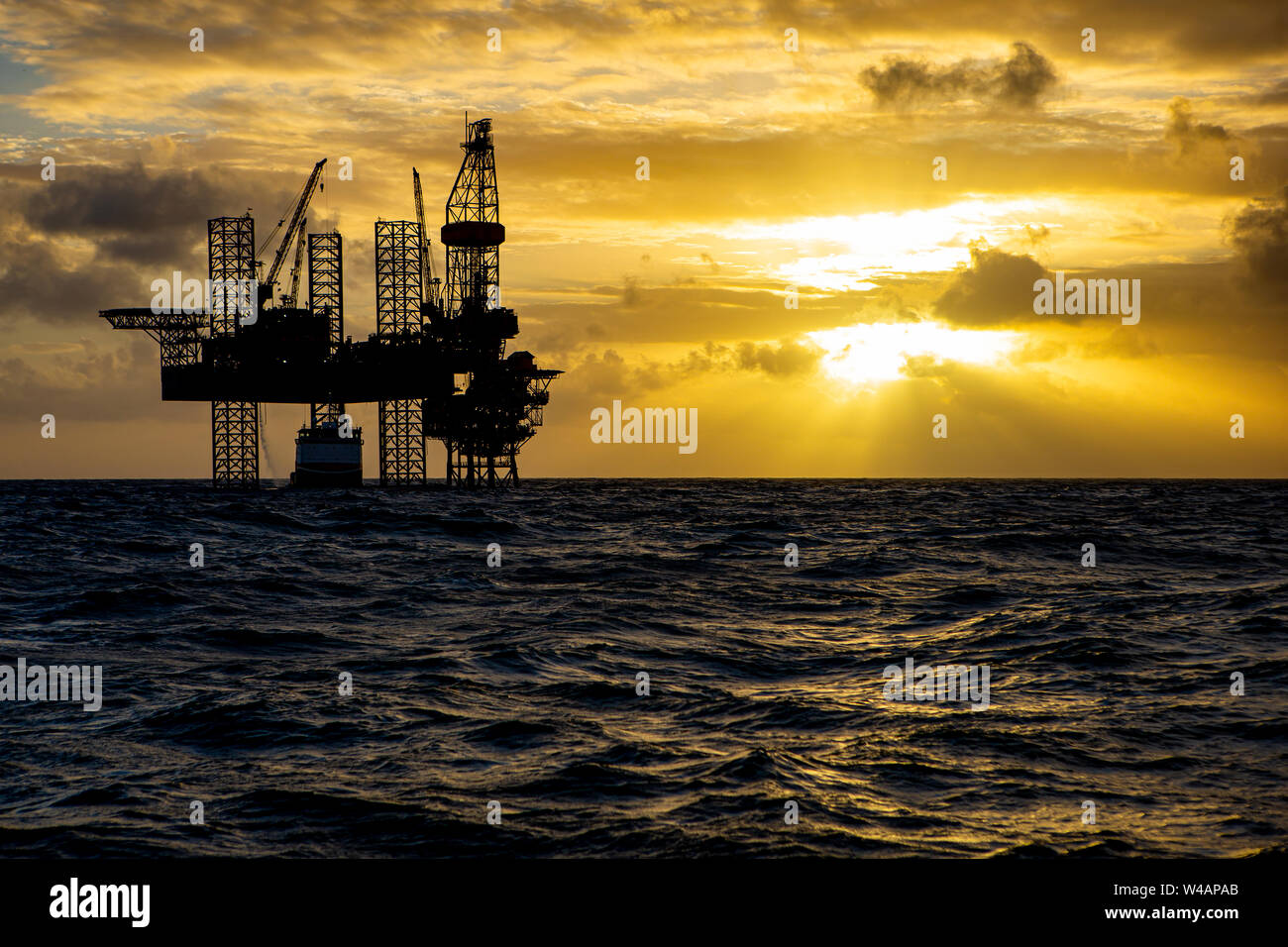 Offshore Bohrinsel bei Sonnenaufgang mit Arbeit Schiff Stockfoto
