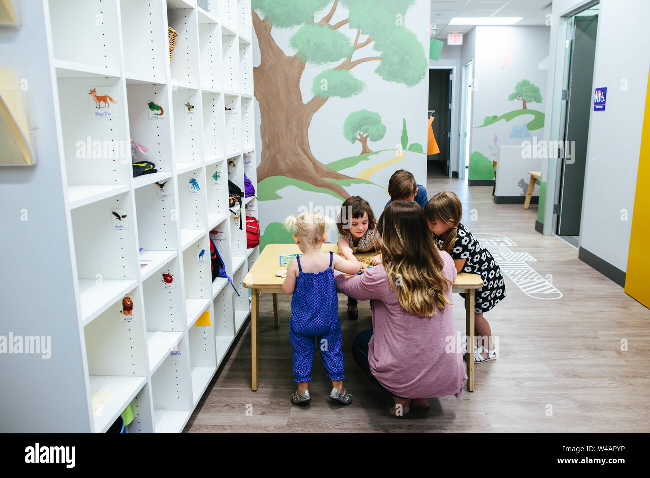 Kinder versammeln sich an einem Tisch mit Lehrer in Bildungseinrichtung Stockfoto