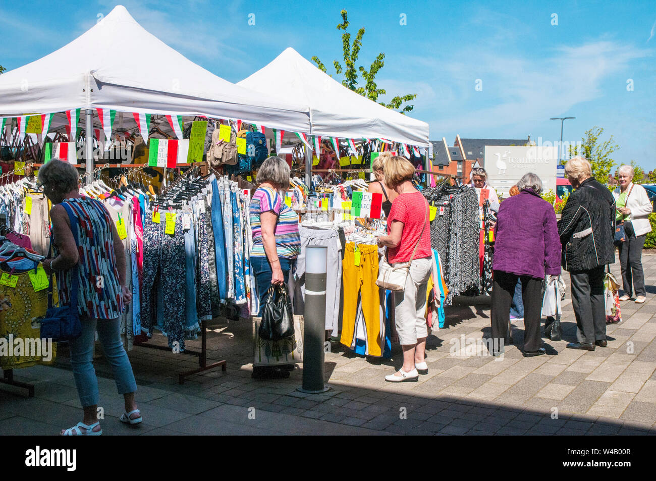 Lady Käufer, um Marktstände mit Kleidung am Markttag in Poulton gefüllt le Fylde Lancashire England Großbritannien Stockfoto