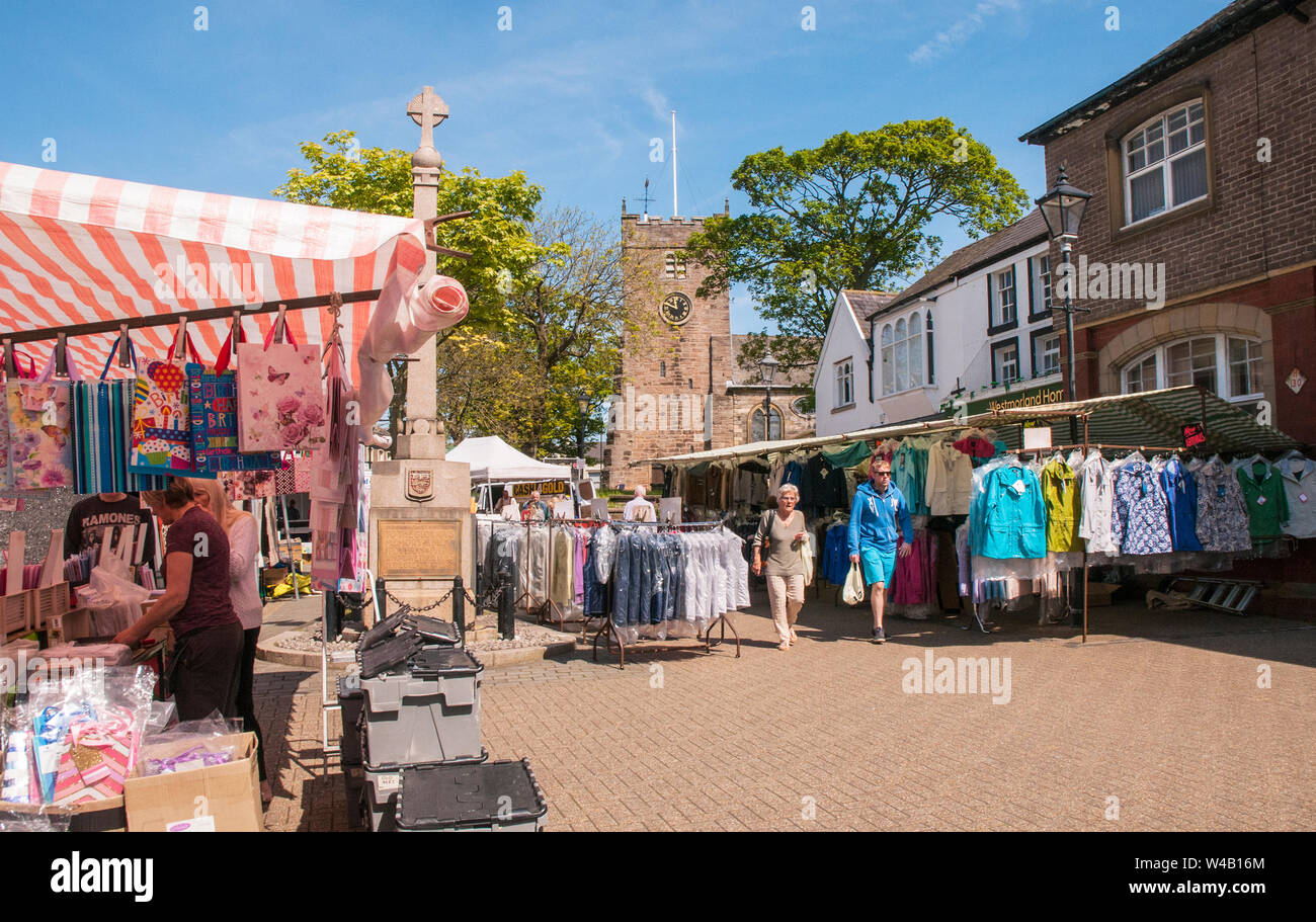 Mann und Frau gehen zwischen den Ständen umliegenden Kriegerdenkmal am Wochenmarkt auf dem Marktplatz in Poulton le Fylde Lancashire England Großbritannien Stockfoto