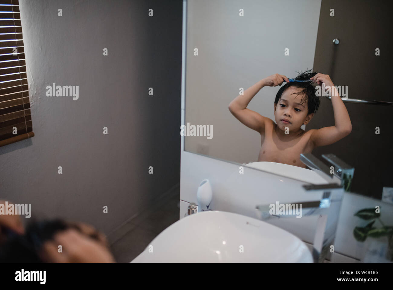 Asian Boy Kämmen vor Spiegel Stockfoto