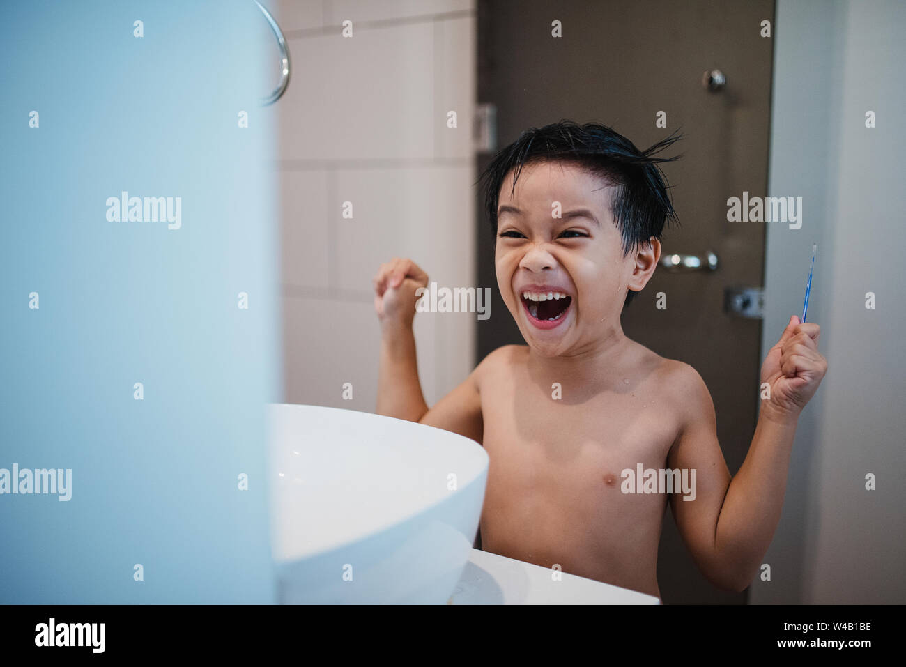 Asian Boy Kämmen vor Spiegel Stockfoto