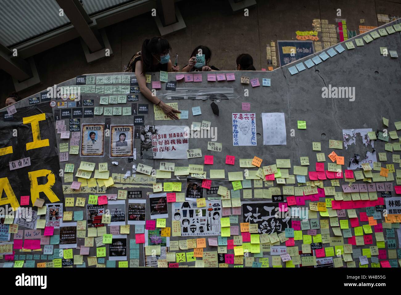 Eine Frau Klebstoffe ein Post-it mit Nachrichten gegen die Auslieferung Bill und pro-Demokratie in einem Lennon Wand im gesetzgebenden Rat Gebäude. Hong Kong Demonstranten versammelten für ein weiteres Wochenende der Proteste gegen die umstrittene Auslieferung Rechnung und mit einer wachsenden Liste von Beschwerden, die der Aufrechterhaltung des Drucks auf Chief Executive Carrie Lam. Stockfoto