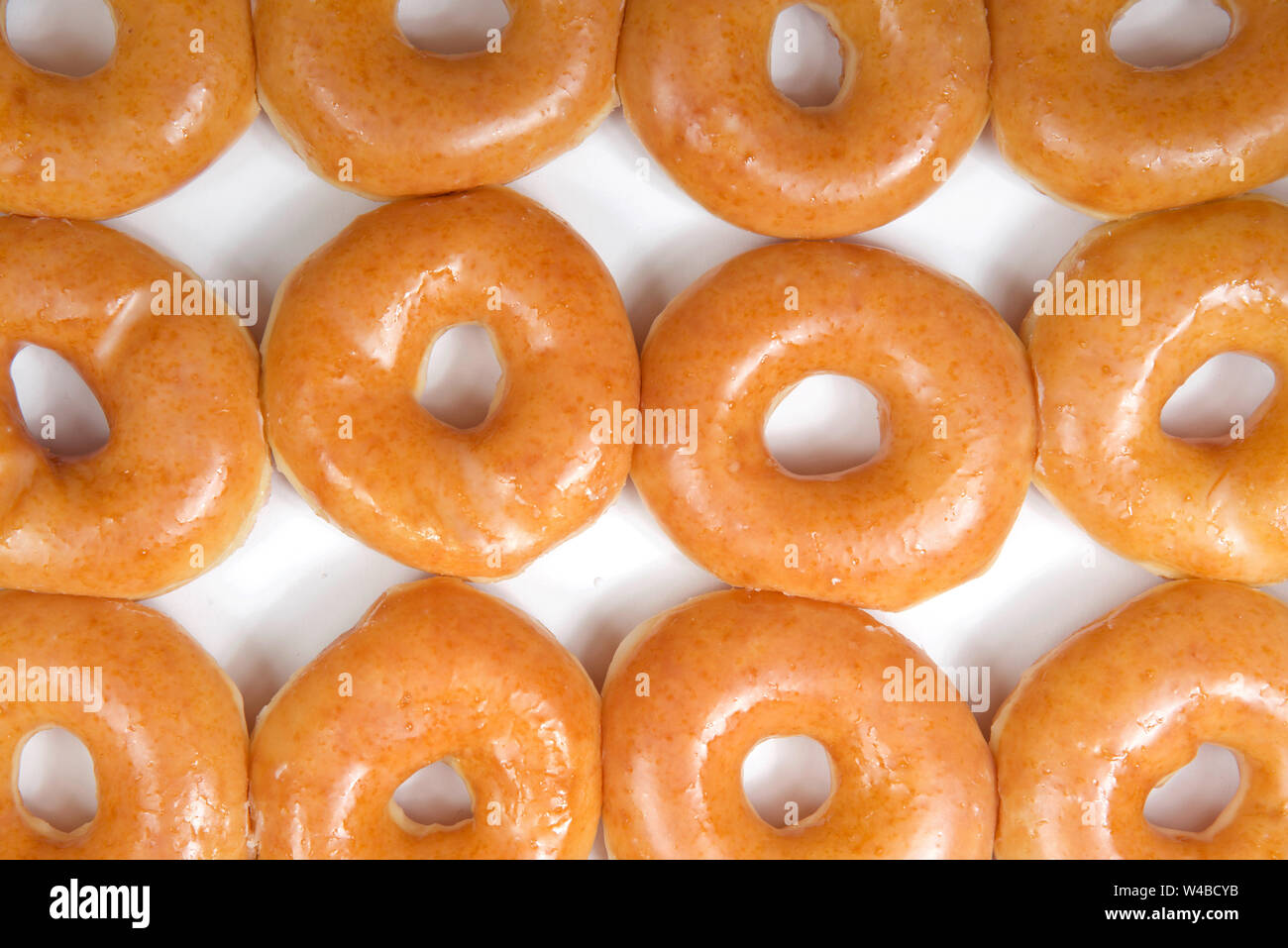 Ansicht von oben flach bis normales glasierte Krapfen in einem weißen Kasten in der Nähe isoliert. Ein Dutzend Donuts. Die ursprüngliche glasierte Krapfen Völker Lieblings t geblieben ist Stockfoto