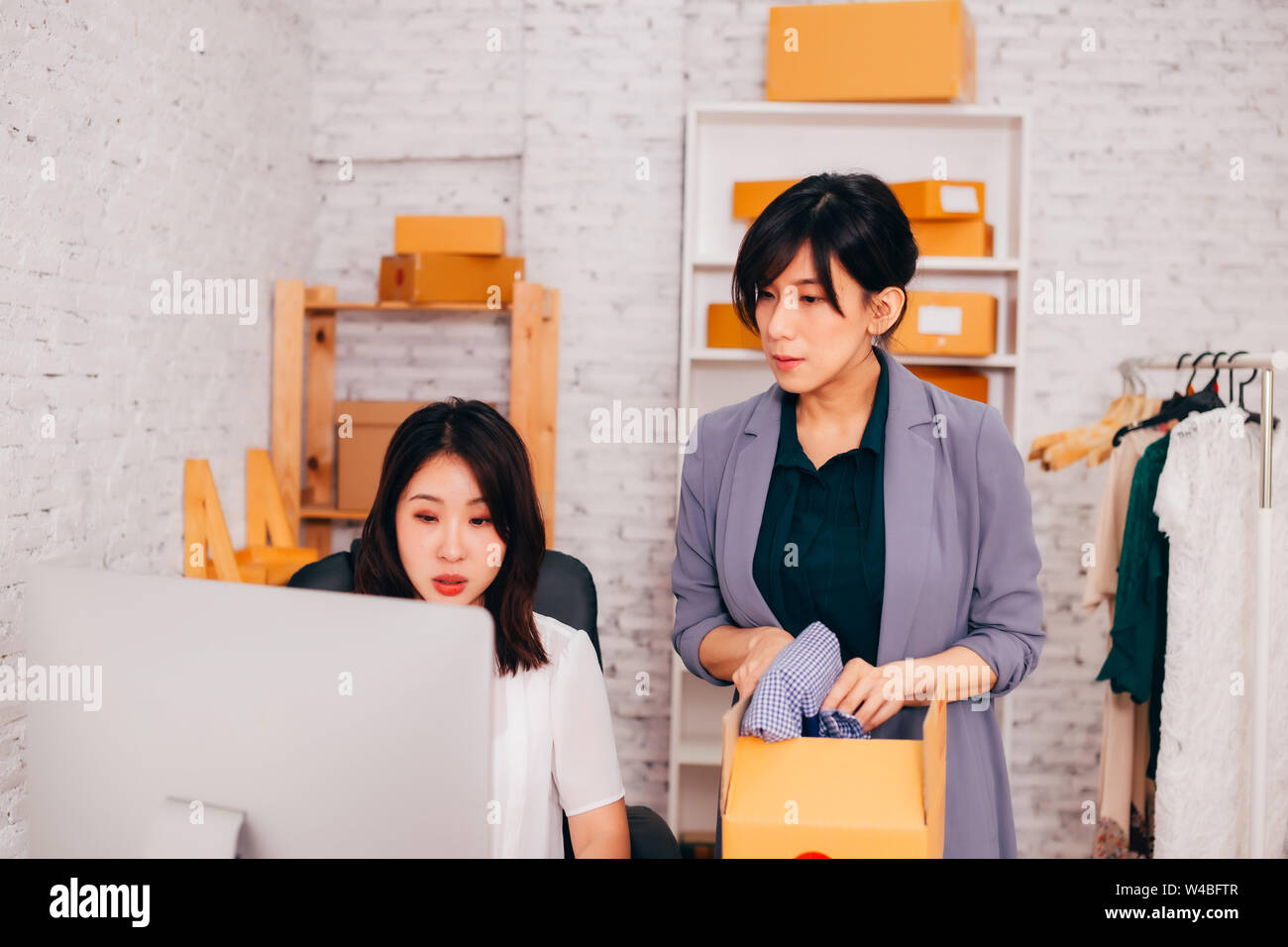 Zwei jungen asiatischen nach Fashion Business weiblichen Anbieter auf dem Handelsmarkt im Amt an den on-line-Unternehmen arbeiten mit Paketen von Kleidung geliefert werden Stockfoto