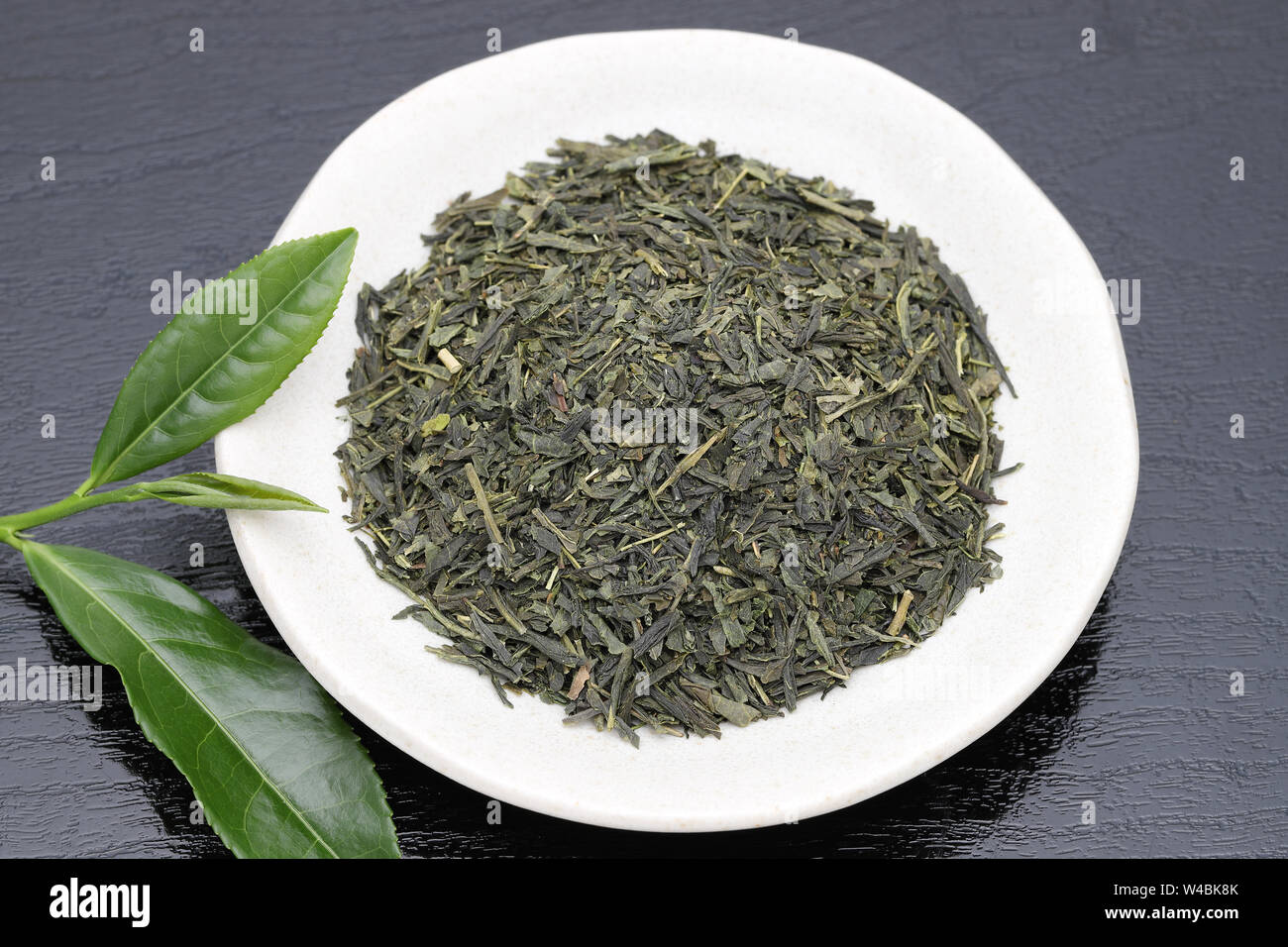 Getrocknete Teeblätter mit grünem Tee Blätter auf schwarzem Hintergrund Stockfoto