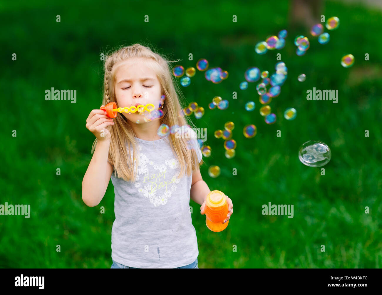 Kleine Mädchen spielen mit Seifenblasen im Park Stockfoto