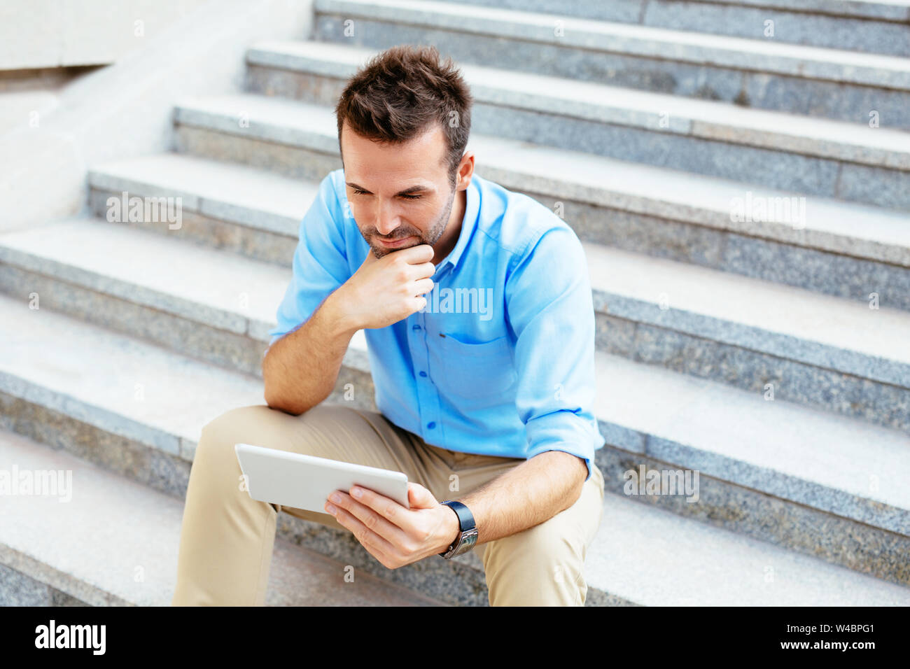 Foto eines Studenten mit einem Tablet und Überarbeitung für seine Prüfung beim Sitzen im Freien Stockfoto
