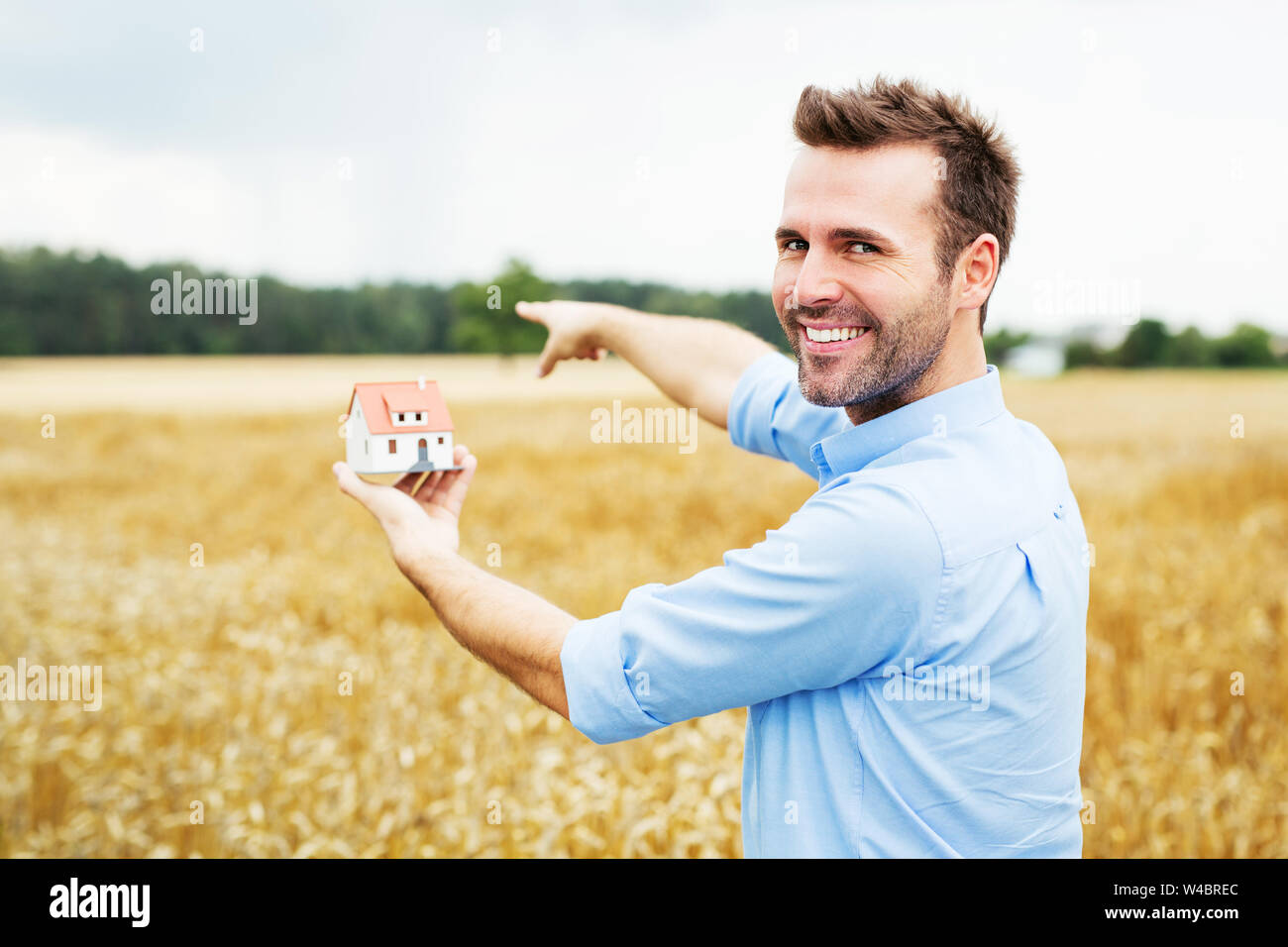 Glückliche Menschen, die sich auf Feld für neues Haus Stockfoto