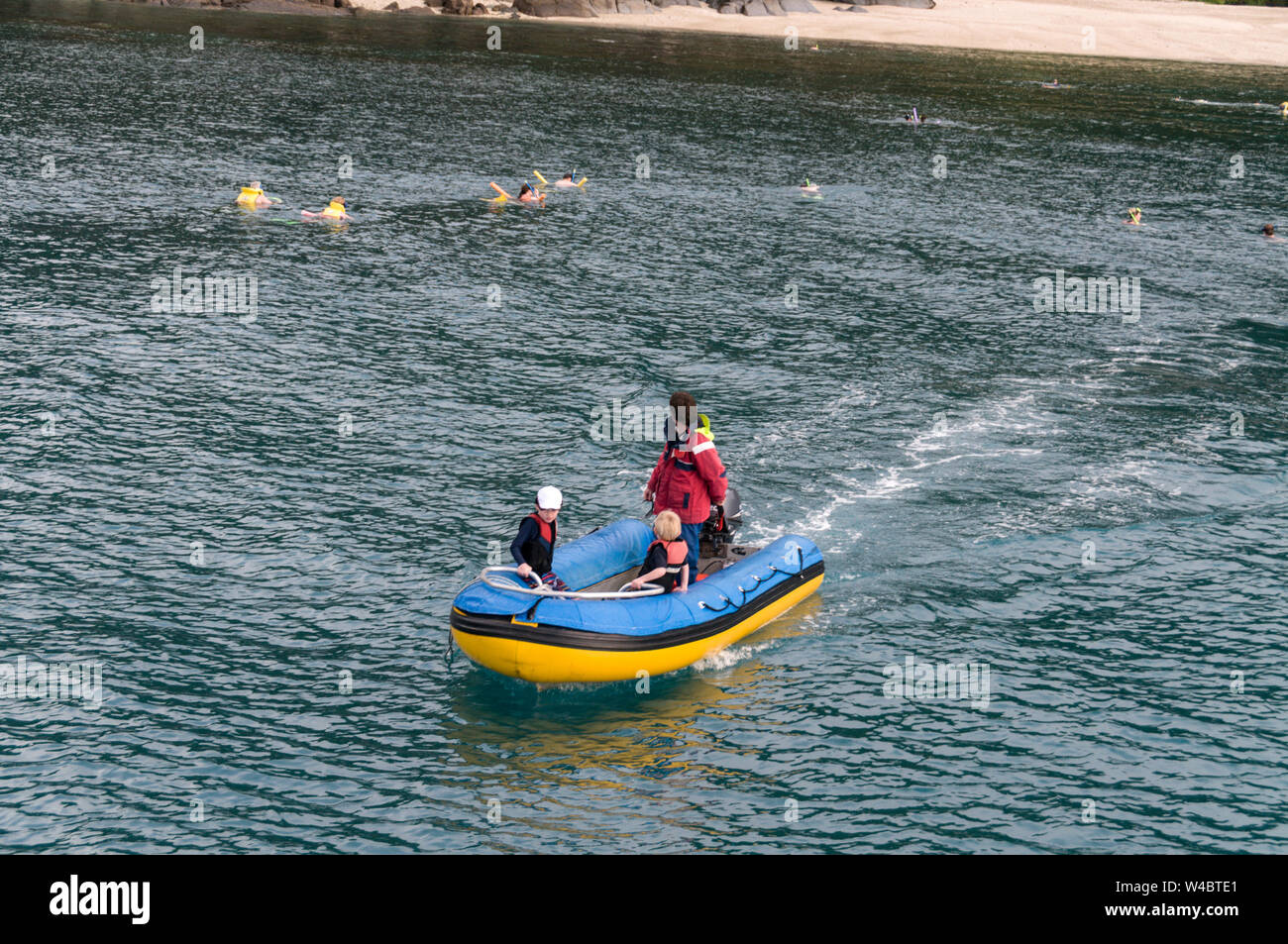 Ein Schlauchboot mit einem klaren Glasboden, tragen ein paar Ausflügler zurück zum Boot, während andere, Schnorcheln in den flachen Gewässern um. Stockfoto