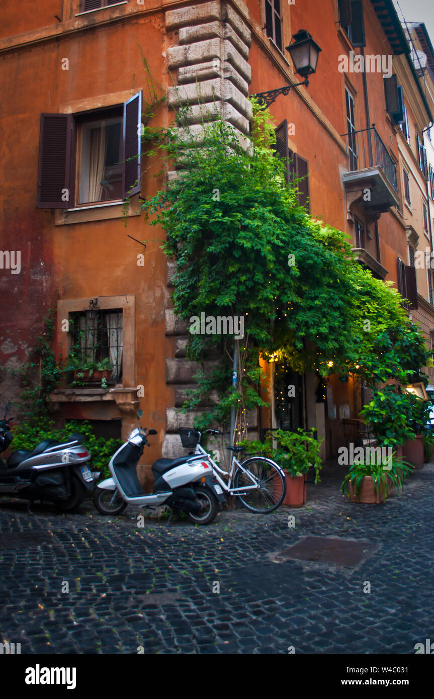 Ein Fahrrad und Roller in der Innenstadt von Rom, Italien, in der Nähe ein gemütliches Cafe mit