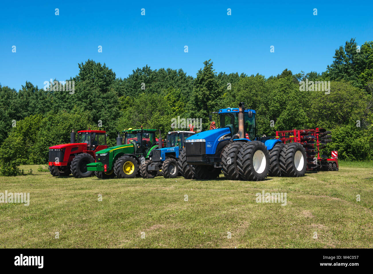 Traktor New Holland, auf das Feld in der russischen Dorf, an einem sonnigen Tag und blauer Himmel. Russland. Tatarstan. Vom 8. Juli 2019. Landwirtschaftliche Maschinen. Stockfoto