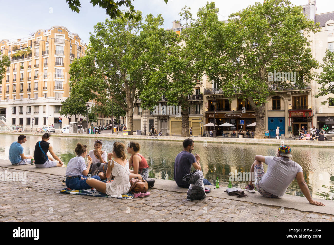 Paris Canal Saint Martin - Leute sitzen entlang des Canal Saint Martin im 10. arrondissement von Paris, Frankreich, Europa. Stockfoto