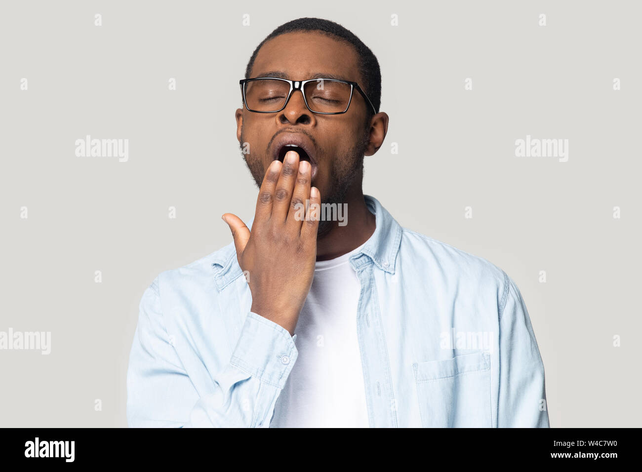 Müde schwarzer Mann fühlen sich schläfrig Abdeckung Mund gähnend Stockfoto